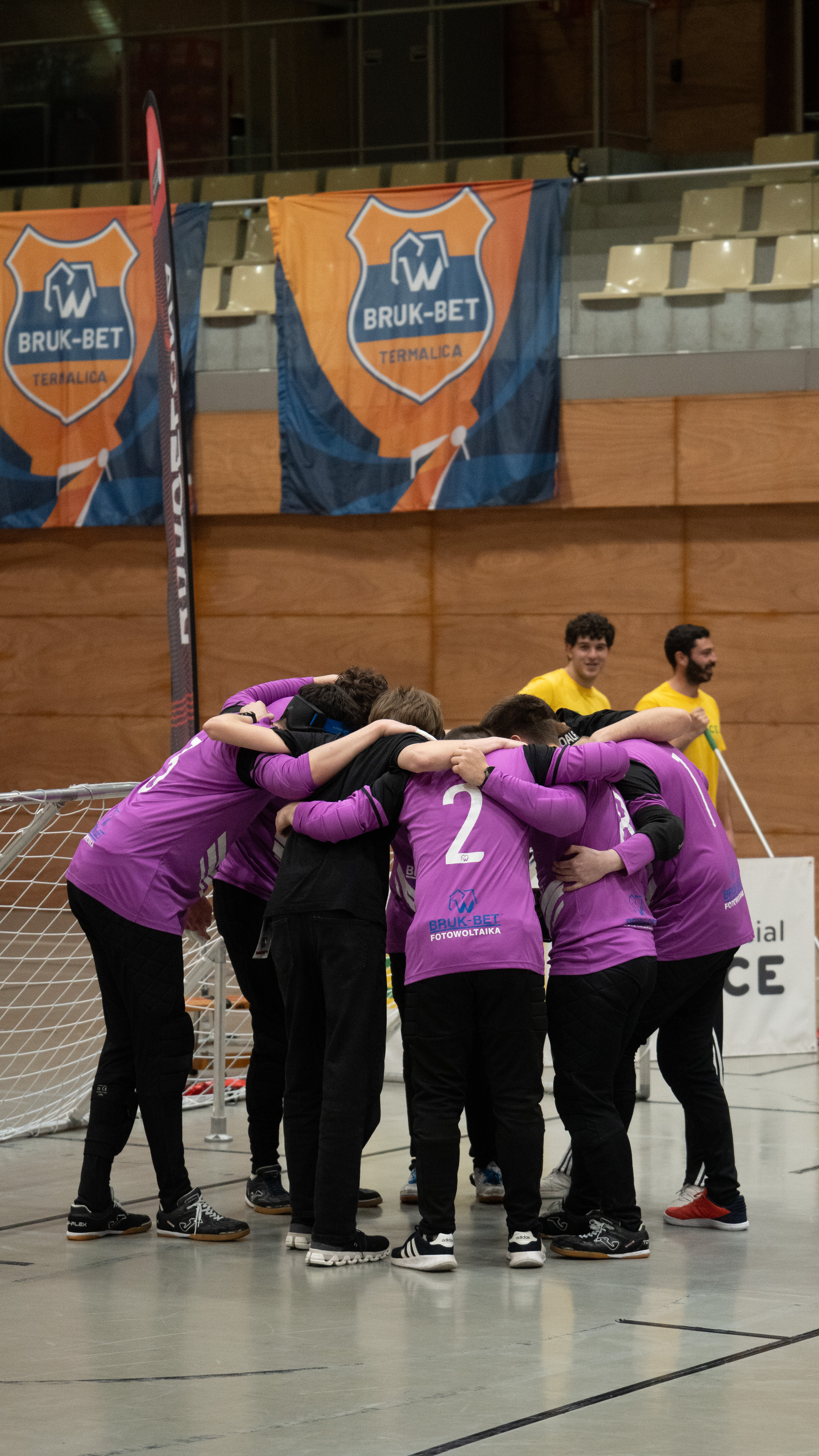 Termalica Krakow players in purple shirts huddle tightly at centre court after their quarter-final win