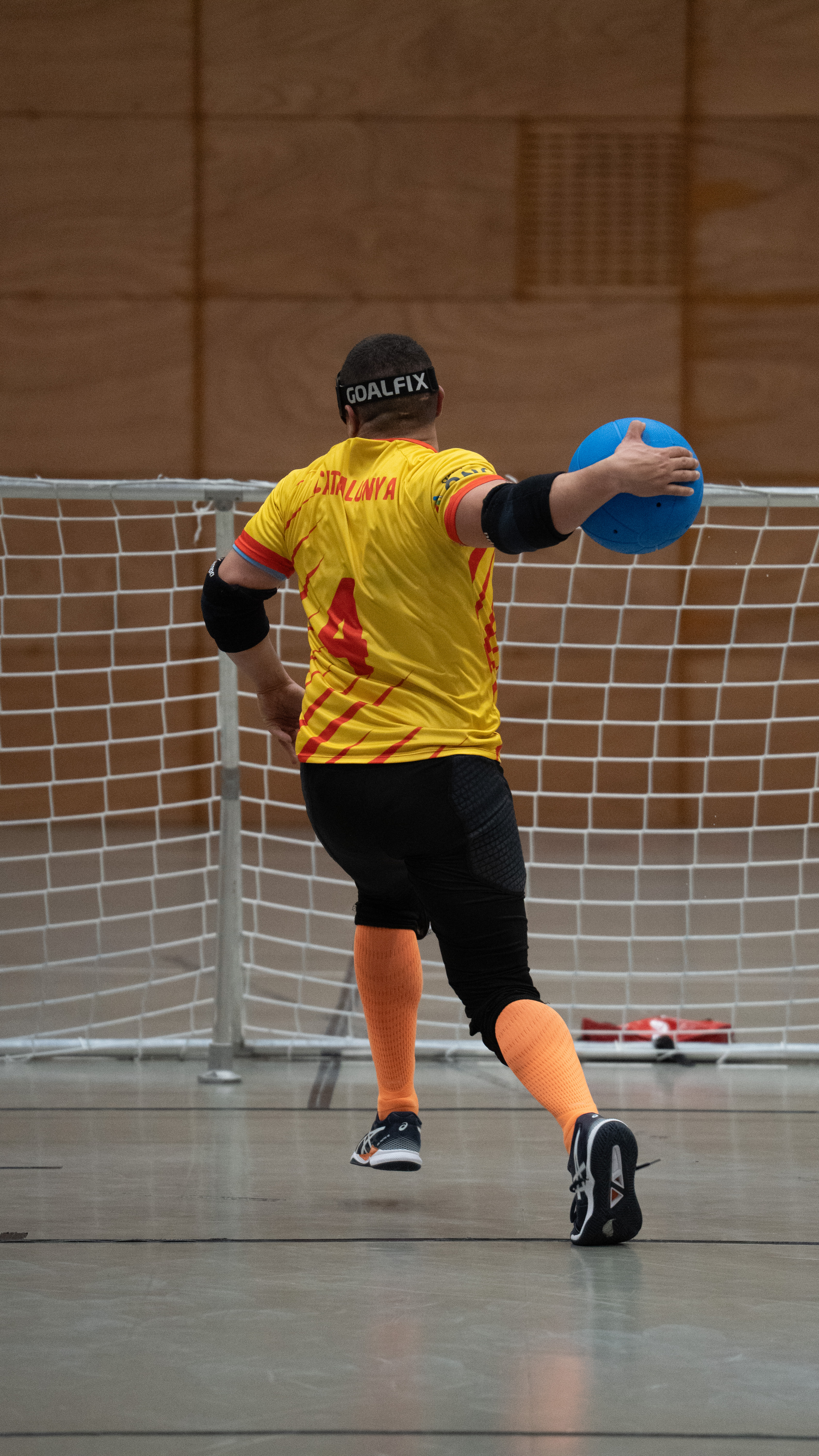Félix Vargas of the hosts Catalunya, wearing number 4, captured mid‑rotation against the backdrop of the goal frame